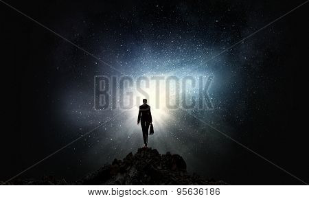 Rear view of businesswoman standing on top and looking in sky