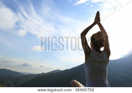 young yoga woman sit meditation on sunrise mountain peak rock