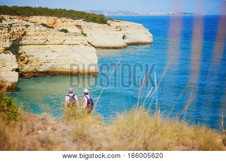 Couple of tourists enjoying scenic view of rocks beach and sea in Algarve south of Portugal