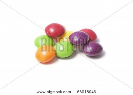 Few colorful small rounded candies on white background