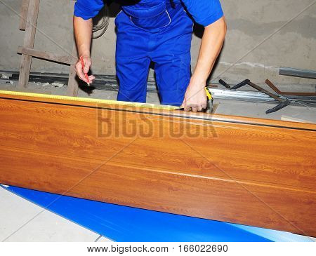 Garage Door Installation. Constructor use a rulerand pencil to verify correct installation on garage door panel. Install garage door.