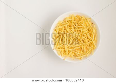 Potato Sticks into a bowl on white background