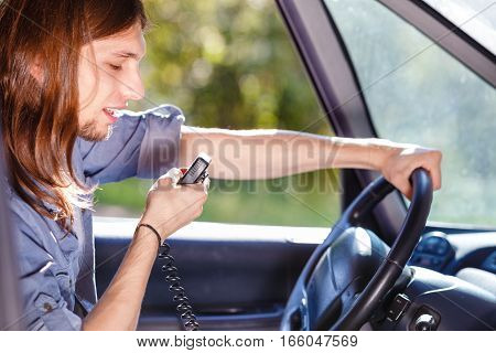 Talking while drive auto walkie talkie comunication concept. Young man driving car using cb radio