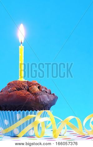 birthday chocolate cake with birthday candle in front of a blue background