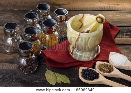 spices in spoons and Jar with mortar on a wodeen background