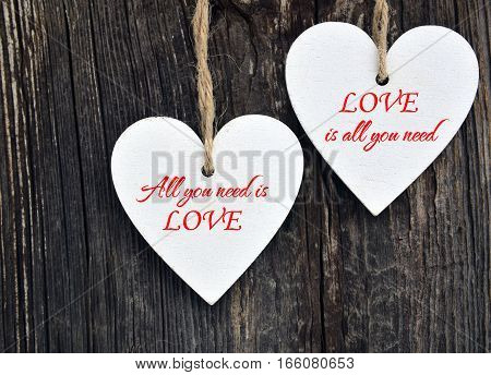 All You Need Is Love.Decorative white wooden hearts on old wooden background.Two Valentine hearts.Valentine's Day or Love concept.Selective focus.