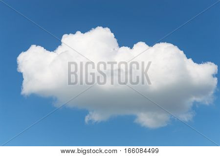 One single fluffy Cumulus cloud in clear deep blue summer sky
