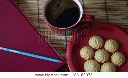 Hot coffee cookies and a book on a wooden table.