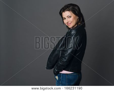 Portrait of beautiful woman with dark hair and green eyes. Dressed in a black leather jacket and jeans.