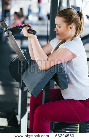 Beginner chubby girl exercising in fitness club
