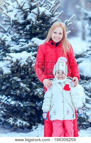 Mother and child girl having fun playing and laughing on snowy winter walk in nature.