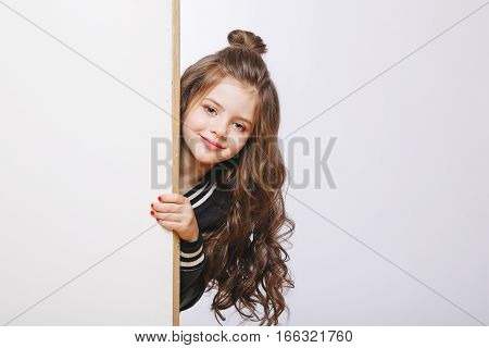 Portrait of little hipster girl looking out. Curly hairstyle. Copy-space. Studio