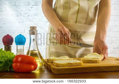 Girl preparing sandwiches and spreads butter on the bread