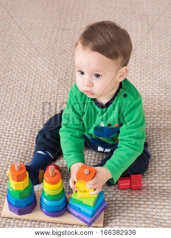 Cute little kid boy playing with lots colorful wooden blocks toy at home.Toddler boy play with toys. Adorable little boy playing with colorful cubes. Happy child playing colorful blocks.