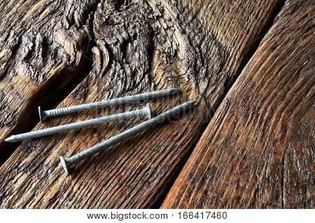 An image of three galvanised nails on a wooden work bench.