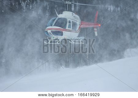 The Helicopter Landed In The Mountains In Winter, Raising A Cloud Of Snow