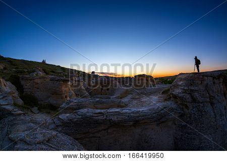 Silhouette of photographer at Writing on the Stone Provincial Park and Aisinaipi National Historic Site in Alberta Canada. The area contains the largest concentration of First Nation petroglyphs (rock carvings) and pictographs (rock paintings).