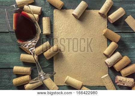 A piece of old parchment paper with a frame of corks and a glass of red wine on a dark background. A retro-styled wine tasting invitation, horizontal design template