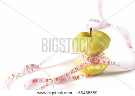 Fresh appetizing apple tied with a measuring tape. Slight reflection, white background, focus on the apple