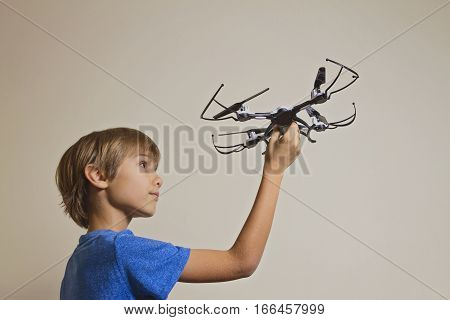 Little kid playing with drone. Boy holding quadcopter in his hand, preparing to fly. Technology, leisure toys concept