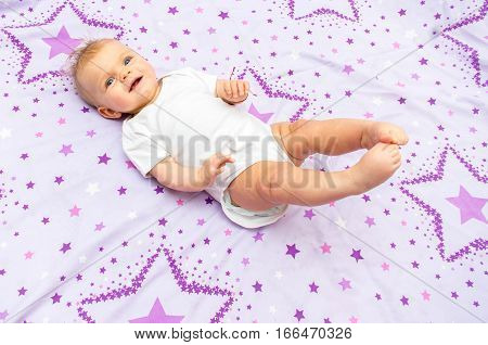 Baby Cheerful Girl Lying On The Bed With A Picture Of The Stars