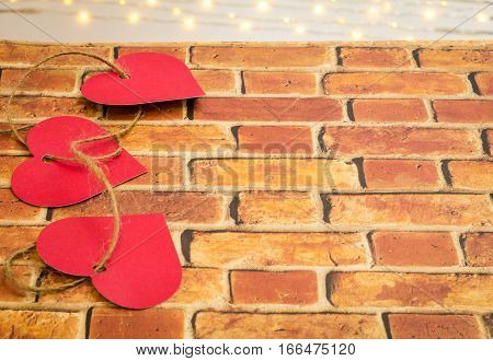 Valentine hearts interwoven with hemp twine on bricks and bokeh lights with room for text