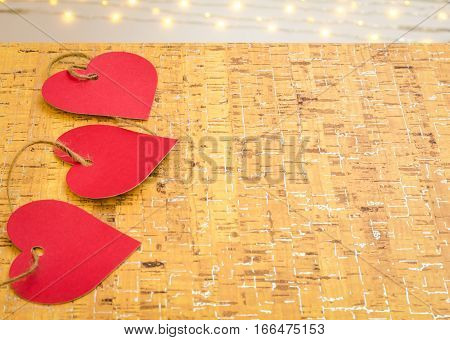 Valentine hearts interwoven with hemp twine on cork board and bokeh lights with room for copy