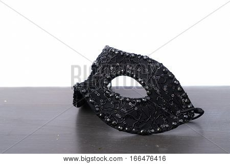 Black mask on wooden table border isolated on white background with copy space