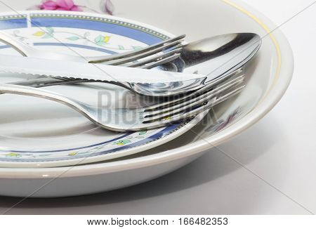 Closeup of clean kitchen utensils - plate knife spoon fork