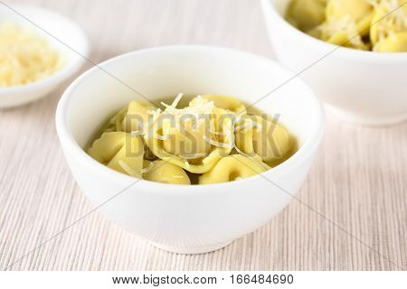 Traditional Italian Tortellini in Brodo (broth) soup with grated cheese on top photographed with natural light (Selective Focus Focus in the middle of the first bowl)