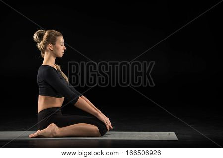 Young woman performing Vajrasana on yoga mat
