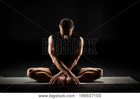 Man performing Baddha Konasana on yoga mat