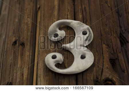 Metal Number Three Nailed to a Wooden Pole