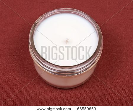 Soy candle in glass jar on red fabric background