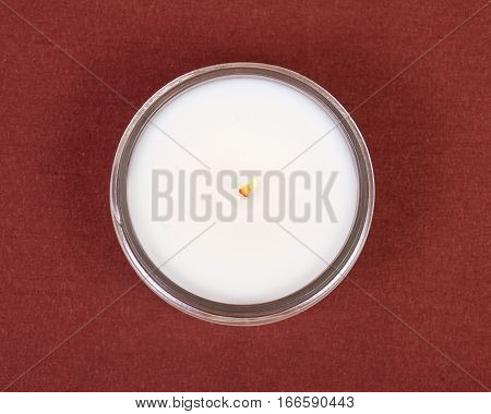 Soy candle in glass jar on red fabric background