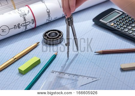 Using engineer compass on graph paper with engineering drawing and tools