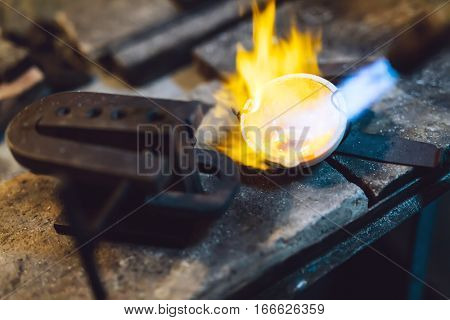 Jeweler melting gold and making jewelry at shop