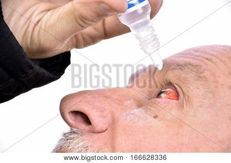 Senior Man Dripping A Red Eye With Eye Drops