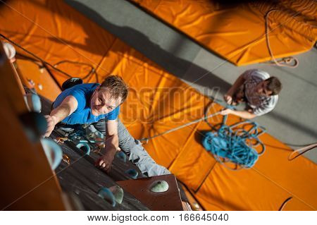 Male Rock-climber Practicing Climbing On Rock Wall Indoors