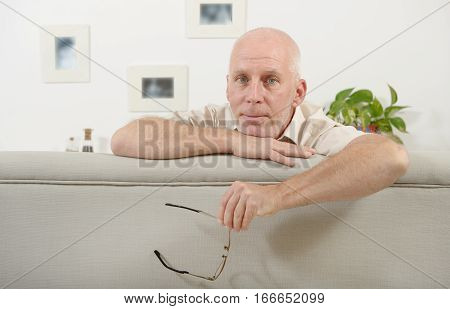 Portrait of a mature man sitting on sfa at home