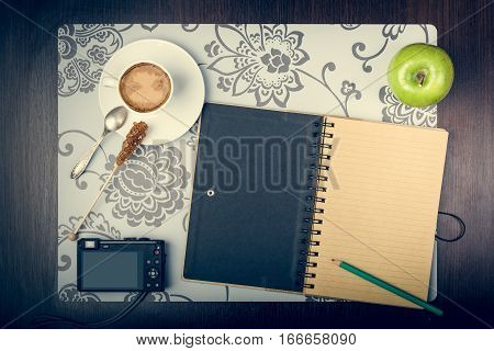 Notepad cup of coffee smartphone and digatal capera on the desktop. Journey planning concept