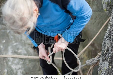 Climber Woman In Safety Harness Tying Rope In Bowline Knot
