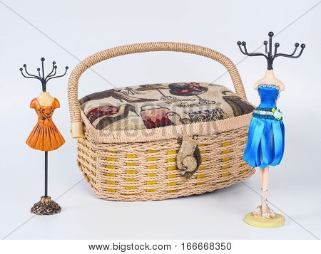 Composition of closed beige-coloured box with two stands for bijouterie isolated on white background. Handmade decoupage box for needlework. Orange and blue mannequin styled stands for bijouterie.
