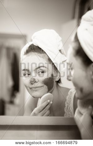 Woman Removing Facial Clay Mud Mask In Bathroom