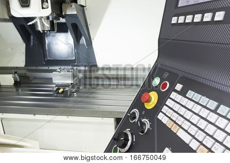 The face milling tool with the raw material work piece on the CNC milling machine in the silver tone effect and the controller panel