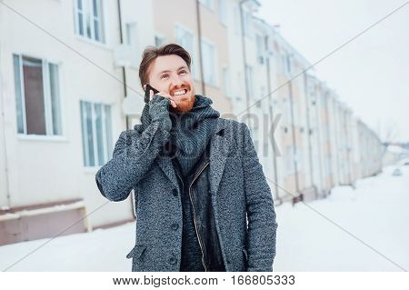 stylish man with a cell phone on the background of the house