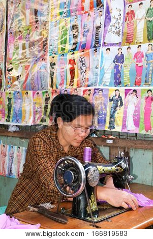 Pyin U Lwin Myanmar - 18 January 2010: Woman working at her sewing-machine at the market in Pyin U Lwin on Myanmar