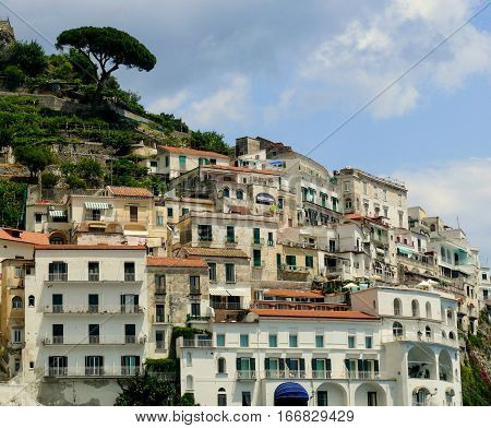 Old Italian town on a mountain. Amalfi terrace houses view. White stone buidings in south Italy. Positano region town from coastline. Red roofs and white walls of italian homes. Travel in Italy