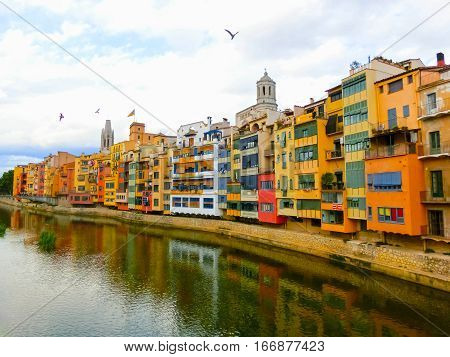 Colorful yellow and orange houses reflected in water river Onyar, in Girona, Catalonia, Spain.
