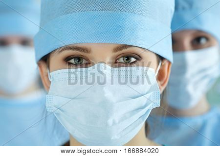 Close up portrait of young female surgeon doctor surrounded by her team. Group of surgeon in operation theatre. Healthcare medical education emergency medical service and surgery concept